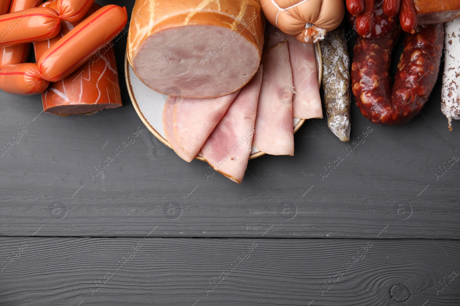 Photo of Different types of sausages on light grey wooden table, above view. Space for text