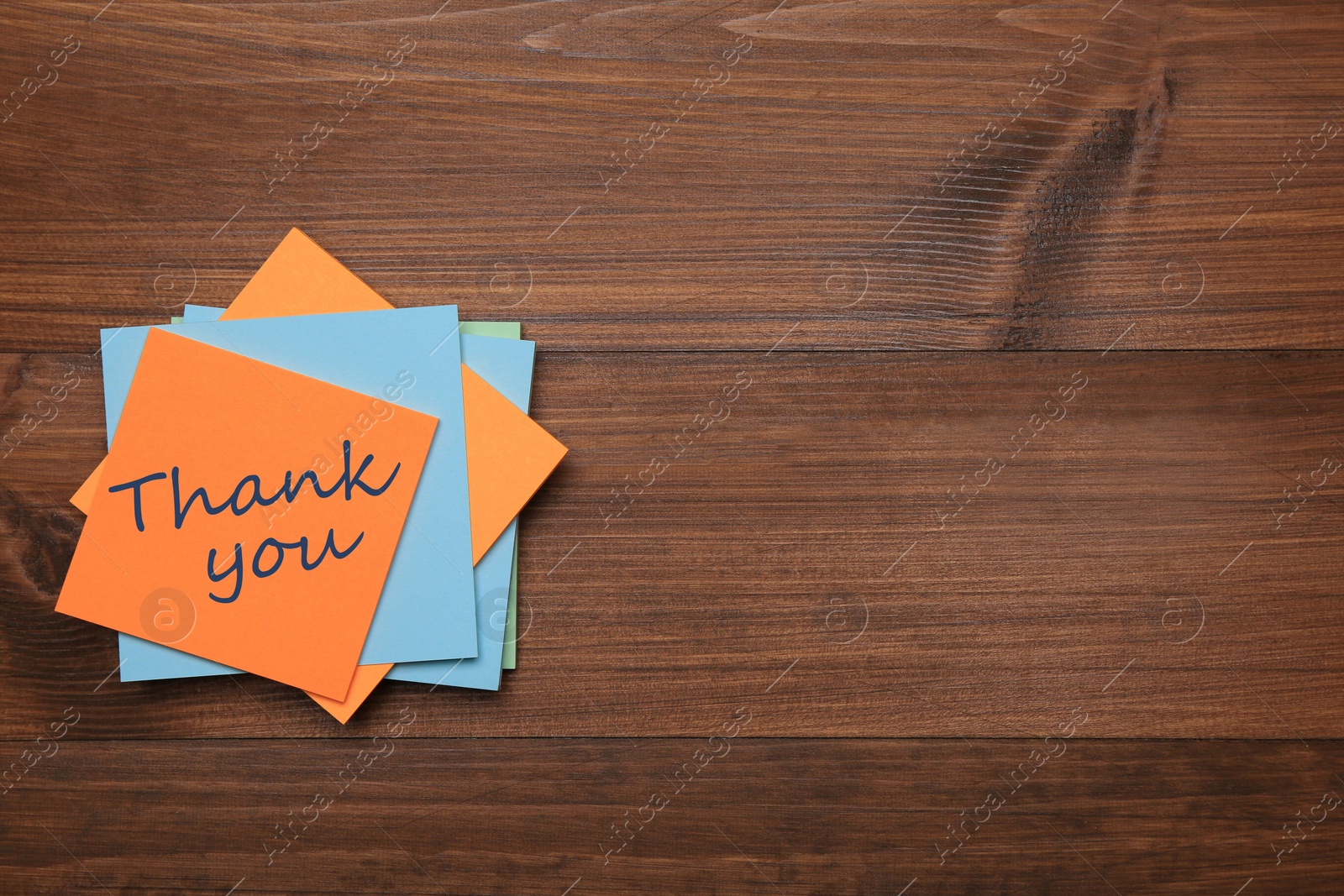 Image of Orange sticker with phrase Thank You on wooden table, top view. Space for text