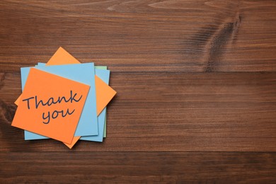 Orange sticker with phrase Thank You on wooden table, top view. Space for text