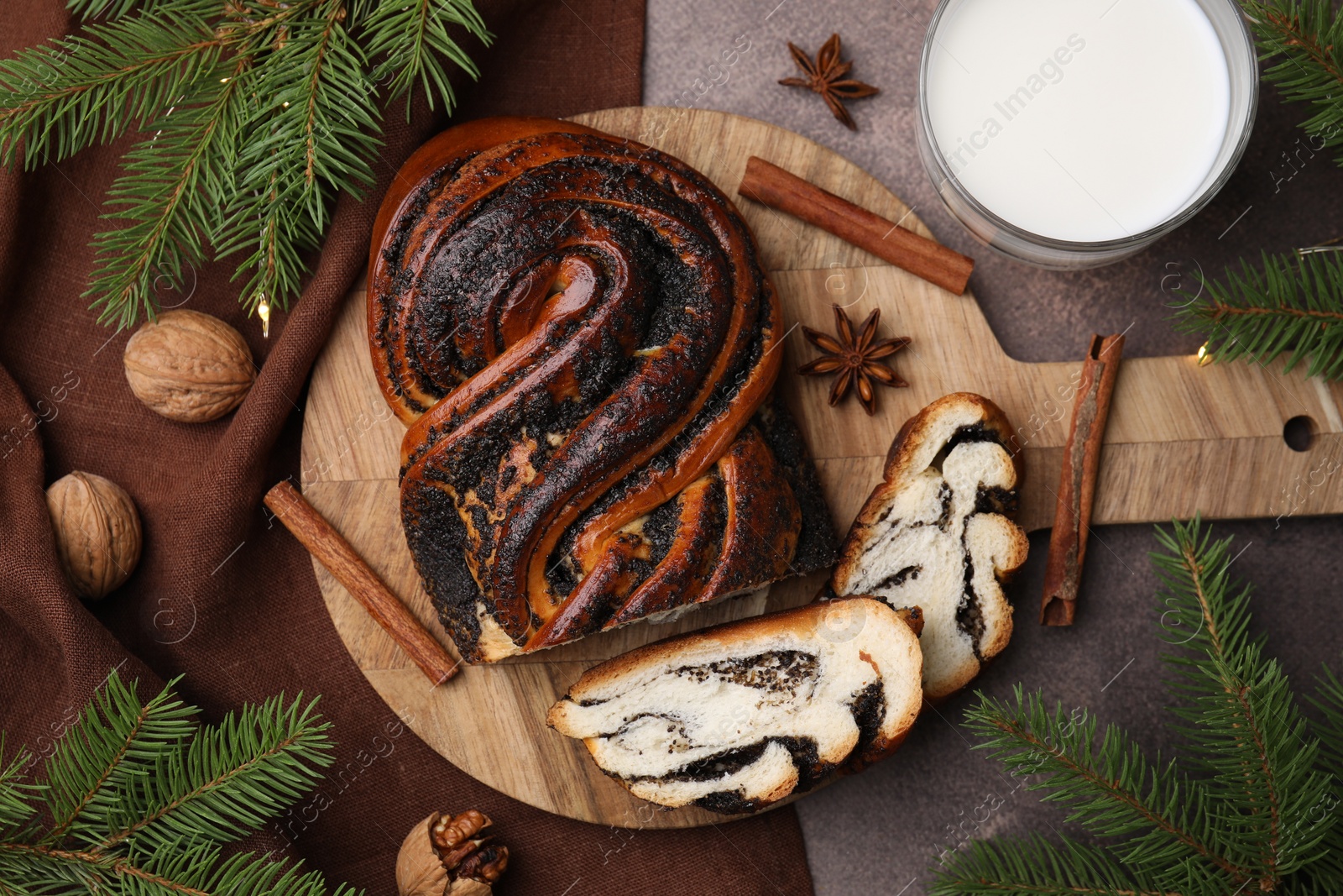 Photo of Flat lay composition with cut poppy seed roll and fir branches on textured table. Tasty cake