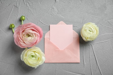 Photo of Beautiful ranunculus flowers with envelope on grey background