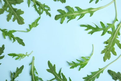 Photo of Frame of fresh arugula on light blue background, flat lay. Space for text