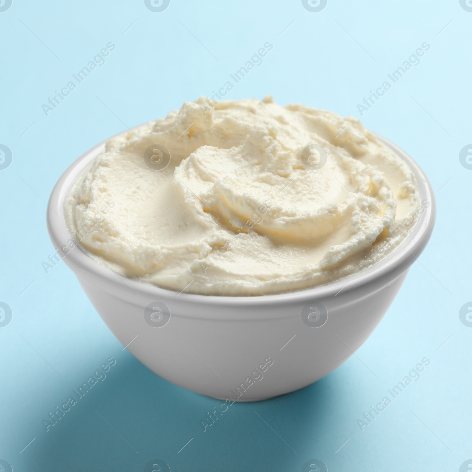 Photo of Bowl of tasty cream cheese on color background