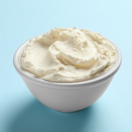 Bowl of tasty cream cheese on color background