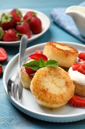 Photo of Delicious cottage cheese pancakes with strawberries, honey and sour cream on light blue wooden table, closeup