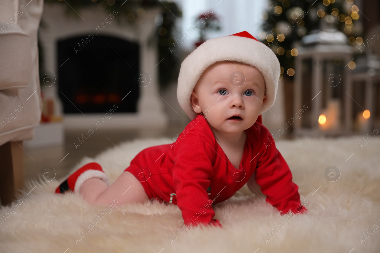 Photo of Cute little baby in red bodysuit and Santa hat on floor at home. Christmas suit