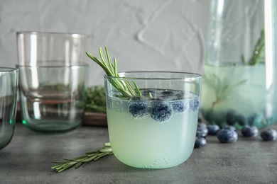 Glass of refreshing blueberry cocktail with rosemary on table