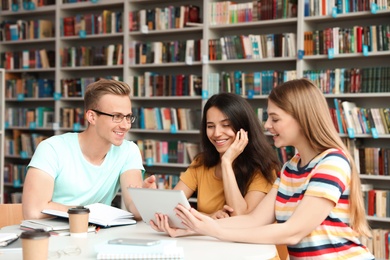 Photo of Young people discussing group project at table in library