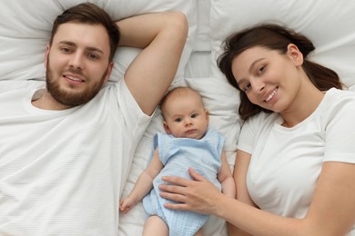 Photo of Happy family. Parents with their cute baby on bed, top view