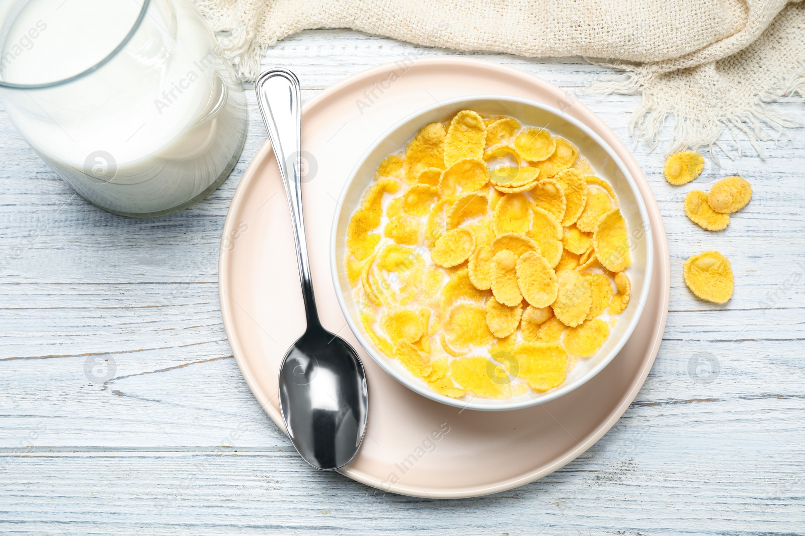 Photo of Tasty corn flakes with milk on white wooden table, flat lay