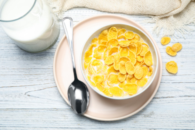 Photo of Tasty corn flakes with milk on white wooden table, flat lay