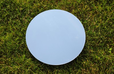 Photo of Spring atmosphere. Round mirror on grass reflecting sky, above view