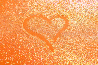 Photo of Heart made with shiny bright glitter on orange background