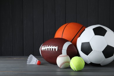 Set of different sport balls and shuttlecock on grey wooden table