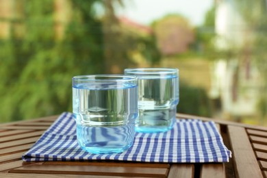Photo of Glasses of pure water on wooden table, space for text