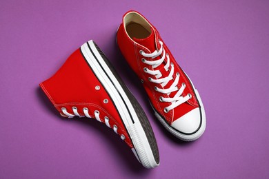 Photo of Pair of new stylish red sneakers on purple background, flat lay