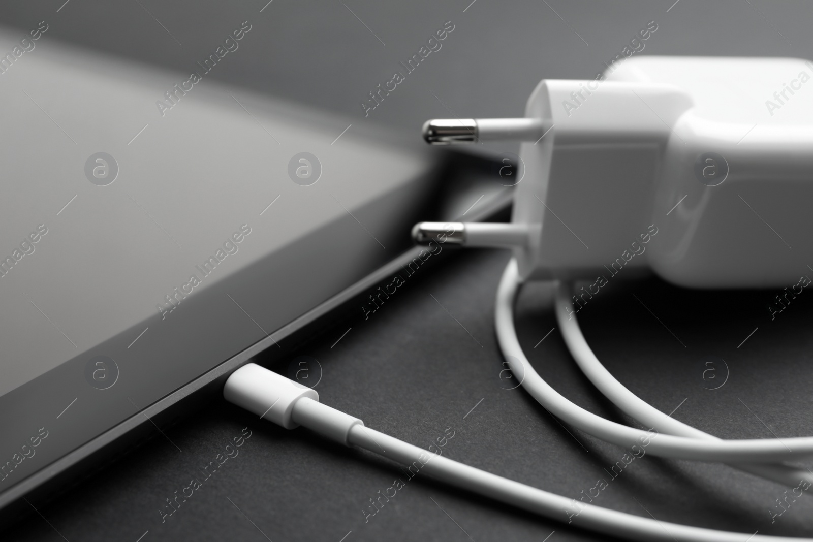 Photo of Tablet and charger on black background, closeup. Modern technology