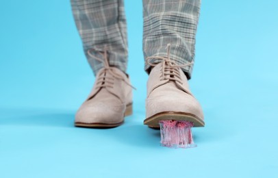 Person stepping into chewing gum on light blue background, closeup