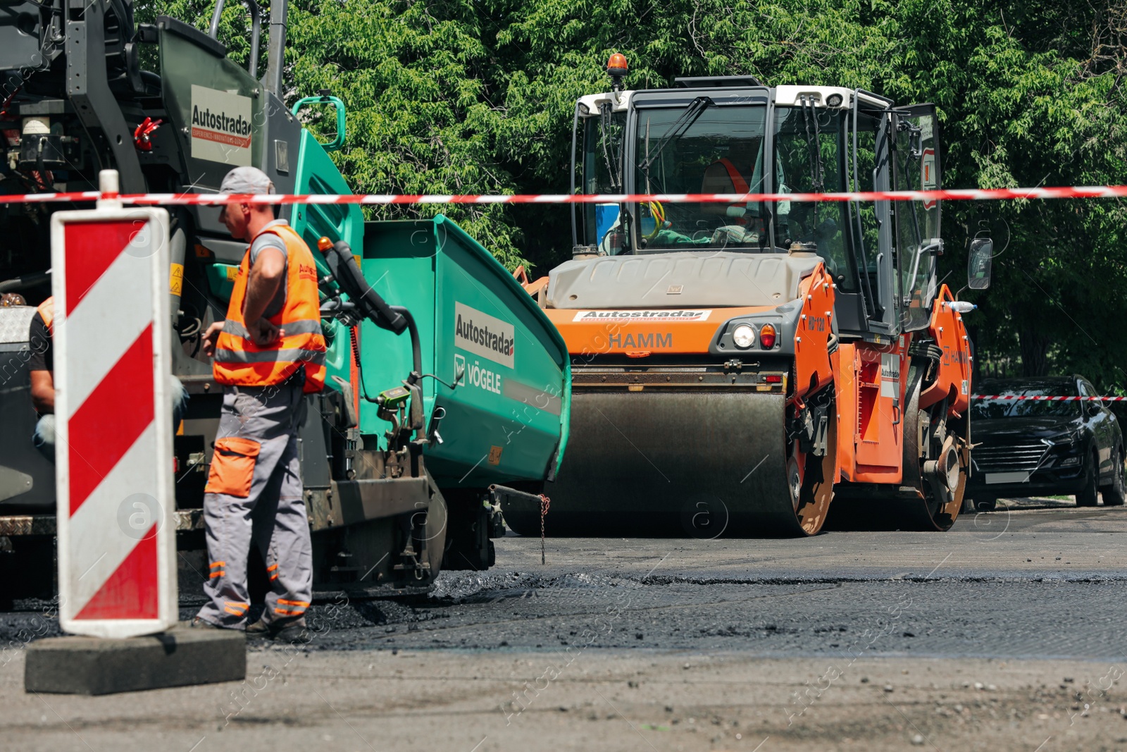 Photo of MYKOLAIV, UKRAINE - AUGUST 04, 2021: Workers with road repair machinery laying new asphalt