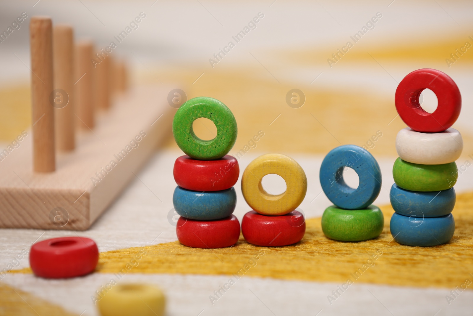 Photo of Stacking and counting game on floor indoors, closeup. Educational toy for motor skills development