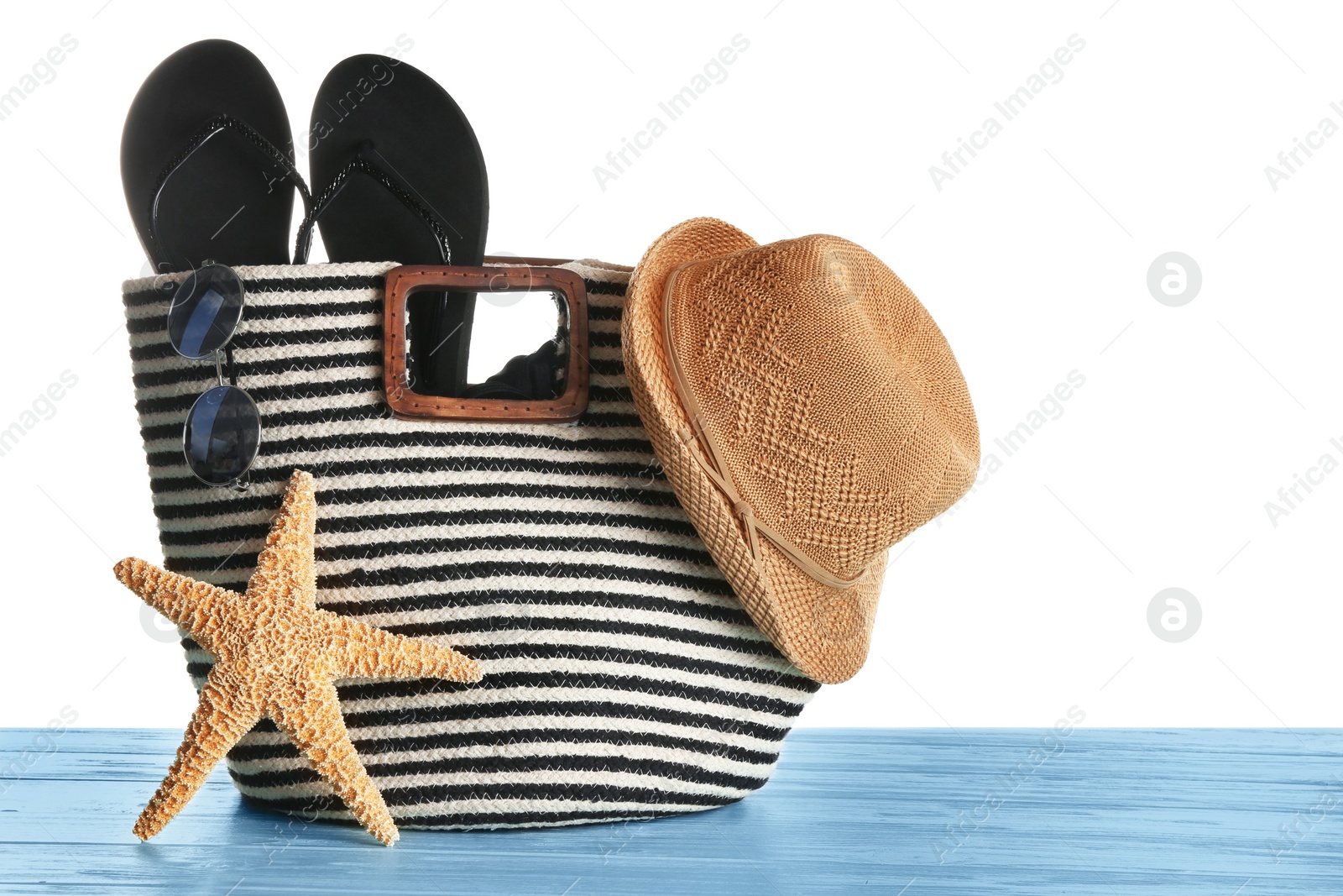 Photo of Set of beach accessories on blue wooden table, white background