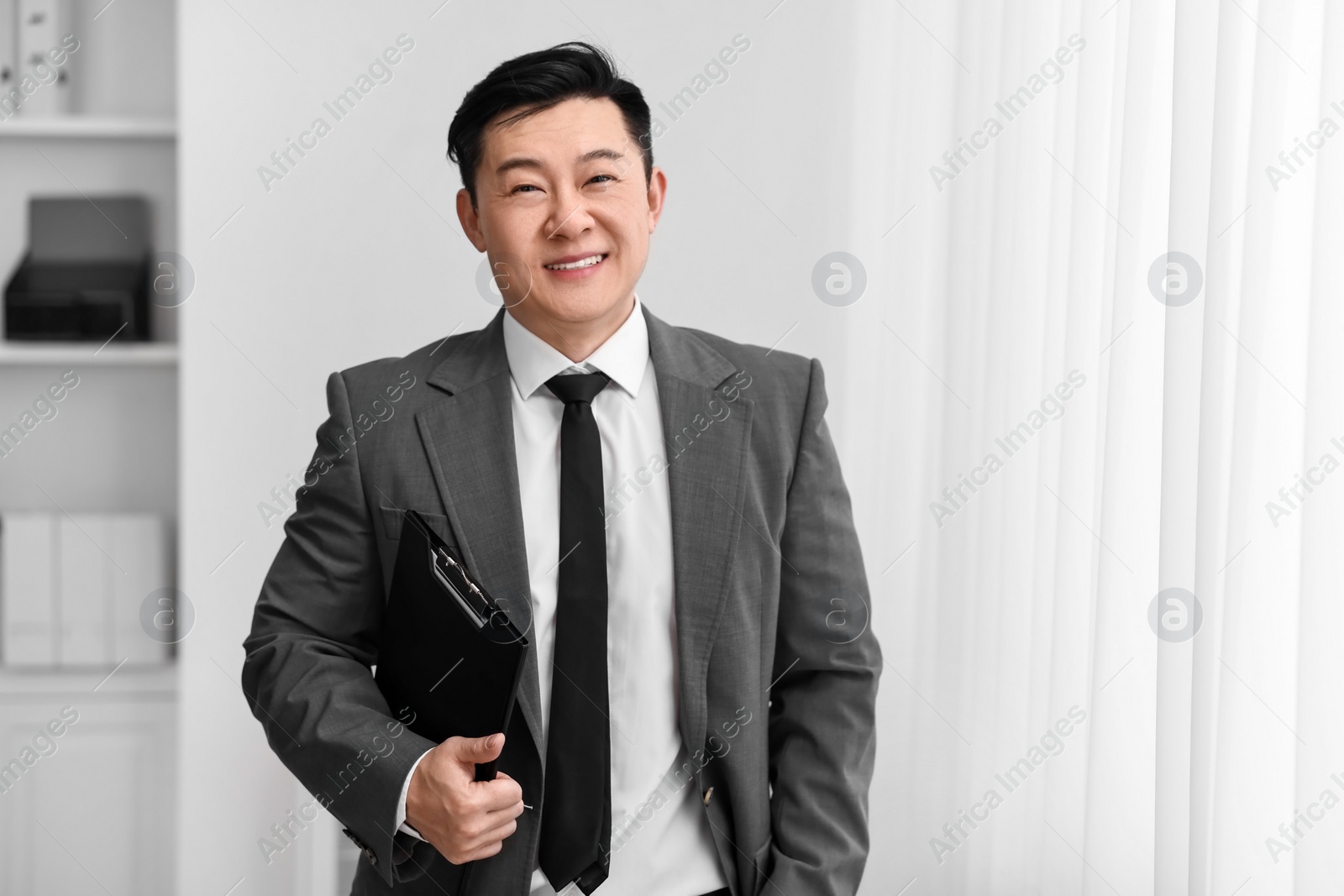 Photo of Portrait of happy notary with clipboard indoors, space for text