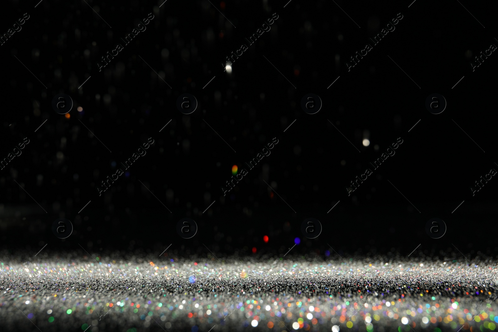 Photo of Shiny colorful glitter falling down on black background. Bokeh effect