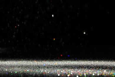 Photo of Shiny colorful glitter falling down on black background. Bokeh effect