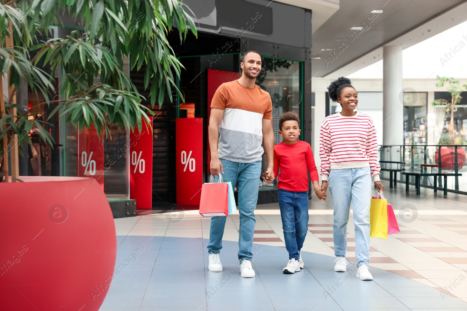 Photo of Family shopping. Happy parents and son with colorful bags in mall