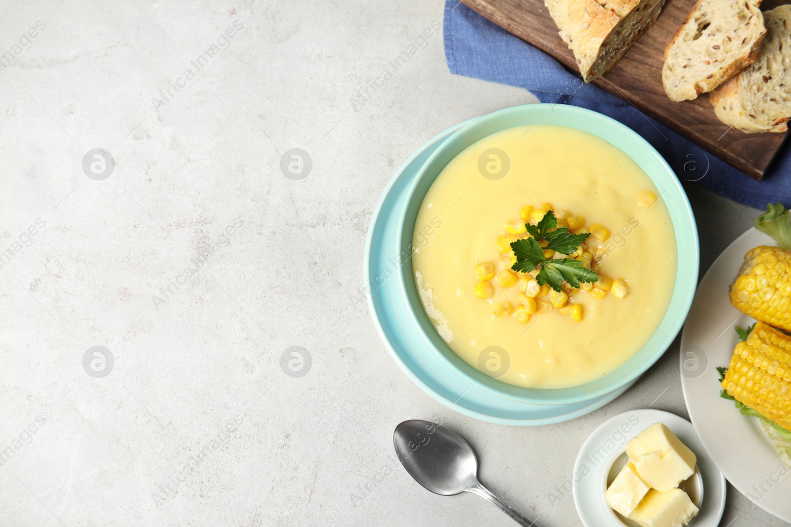 Photo of Delicious corn cream soup served on light grey table, flat lay. Space for text