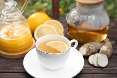 Cup of delicious tea with lemon and honey on wooden table