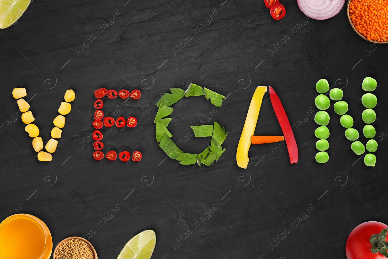 Image of Word VEGAN made of different fresh tasty vegetables on black background, flat lay