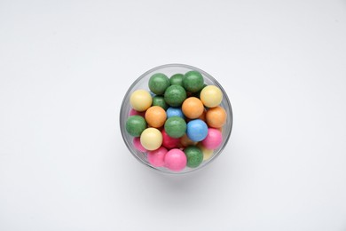 Photo of Bowl with many bright gumballs on white background, top view