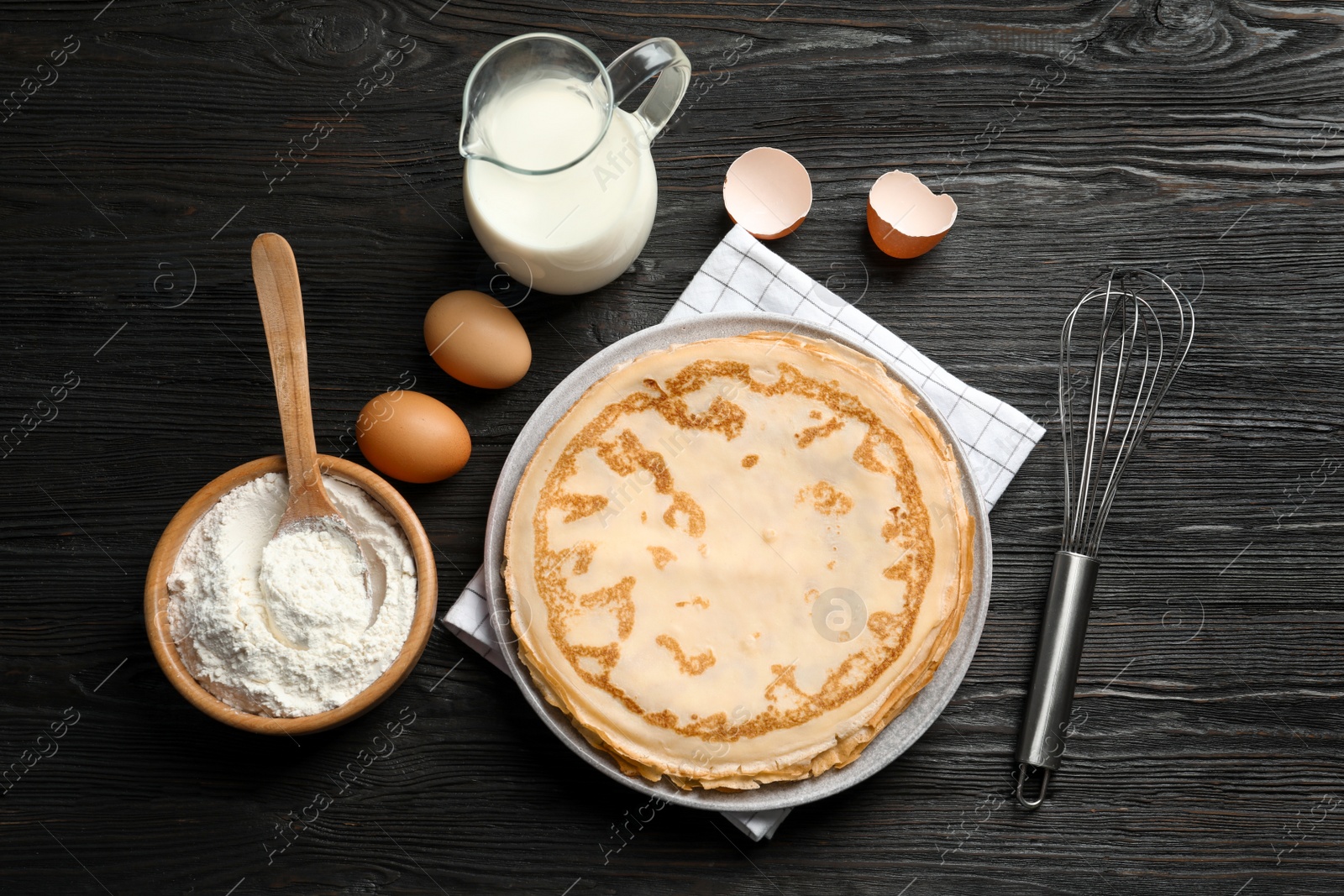 Photo of Flat lay composition with thin pancakes and ingredients on wooden background