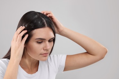 Photo of Emotional woman examining her hair and scalp on grey background. Dandruff problem