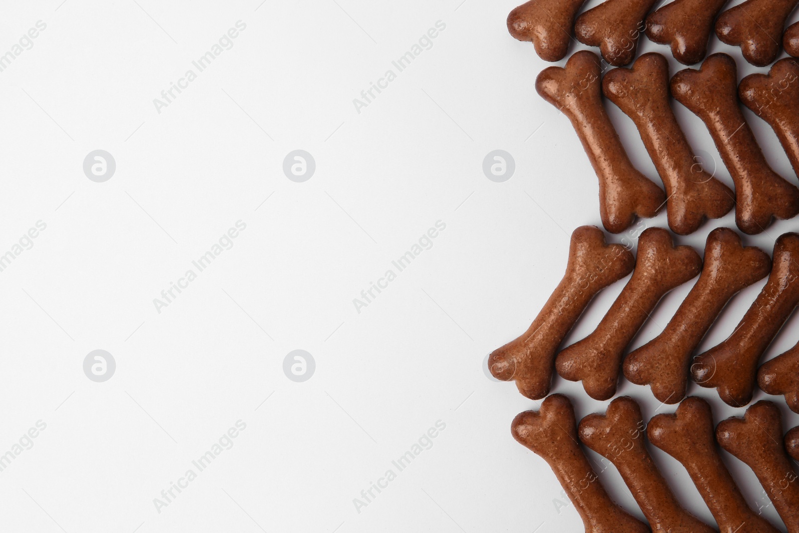 Photo of Bone shaped dog cookies on white background, flat lay. Space for text