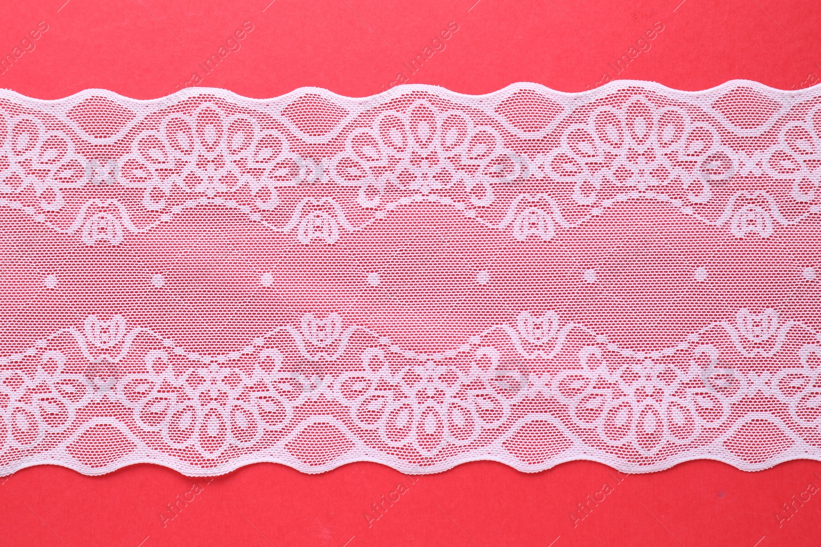 Photo of White lace on red background, top view