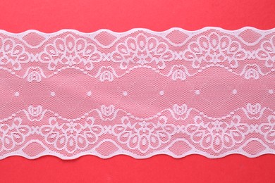 Photo of White lace on red background, top view