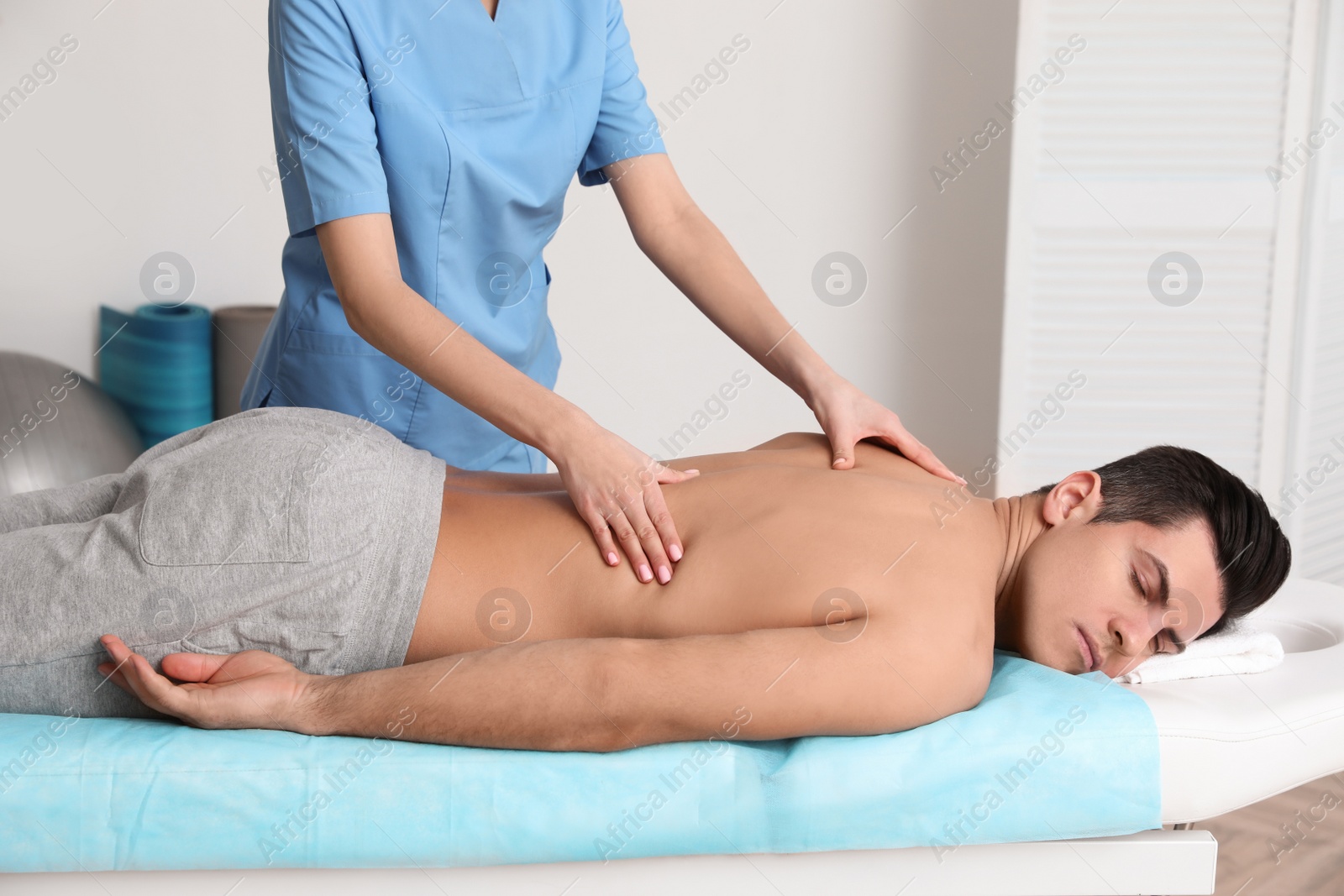 Photo of Orthopedist massaging man's back in clinic, closeup. Scoliosis treatment