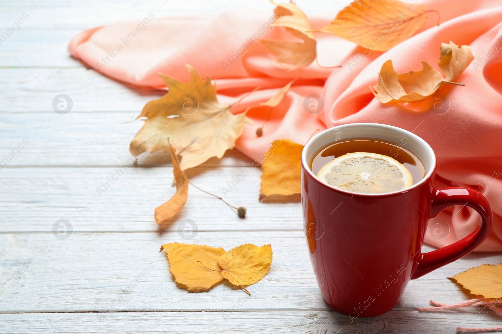 Photo of Cup of hot drink and leaves on white wooden table, space for text. Cozy autumn atmosphere