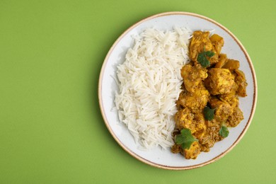 Photo of Delicious chicken curry with rice on green background, top view. Space for text