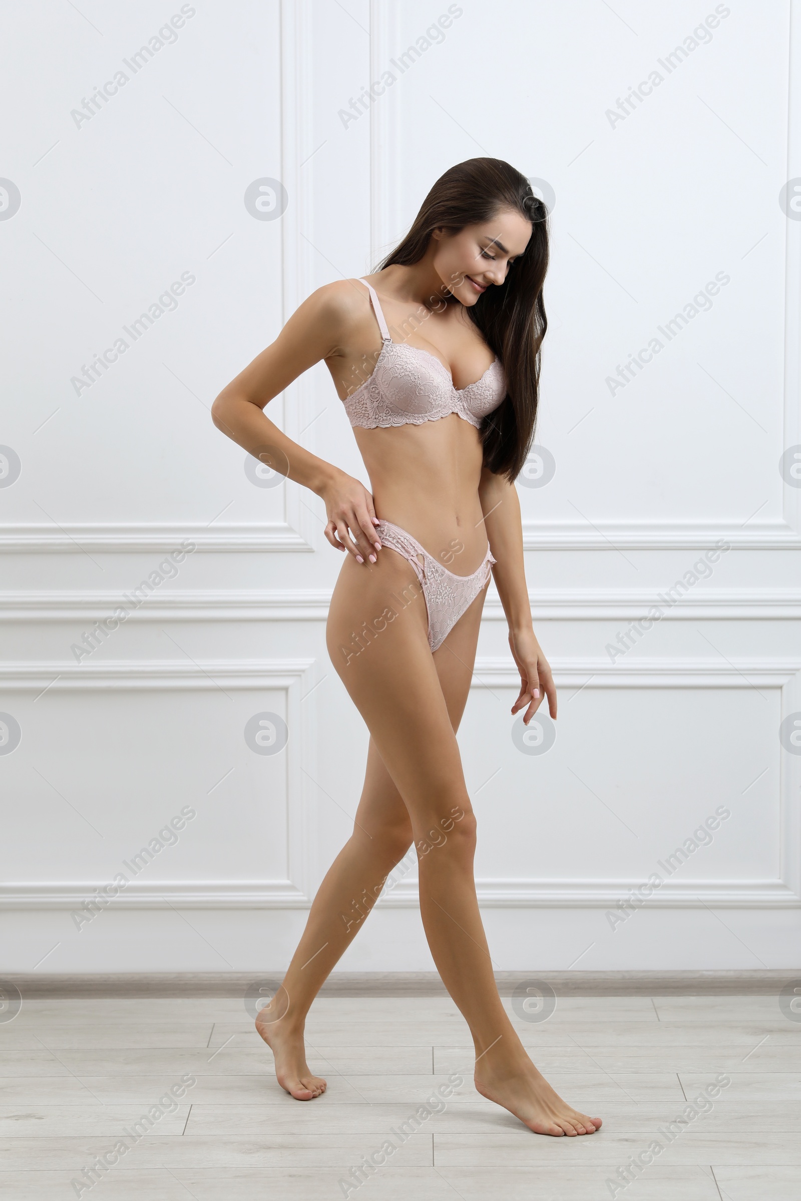 Photo of Young woman in elegant underwear near white wall