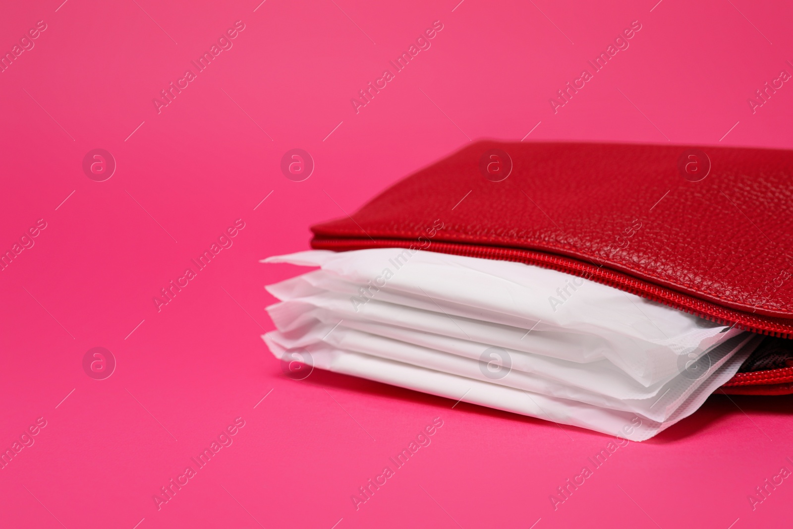 Photo of Red bag with menstrual pads on pink background. Space for text