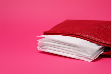 Photo of Red bag with menstrual pads on pink background. Space for text