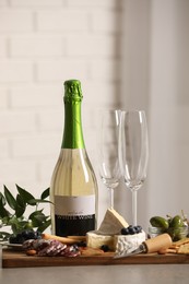 Photo of Bottle of white wine, glasses and delicious snacks on grey table indoors