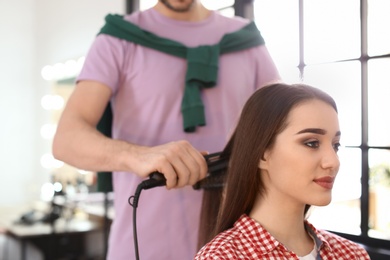 Photo of Professional hairdresser working with client in beauty salon