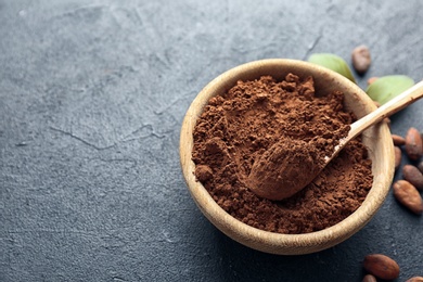 Bowl with cocoa powder on grey background