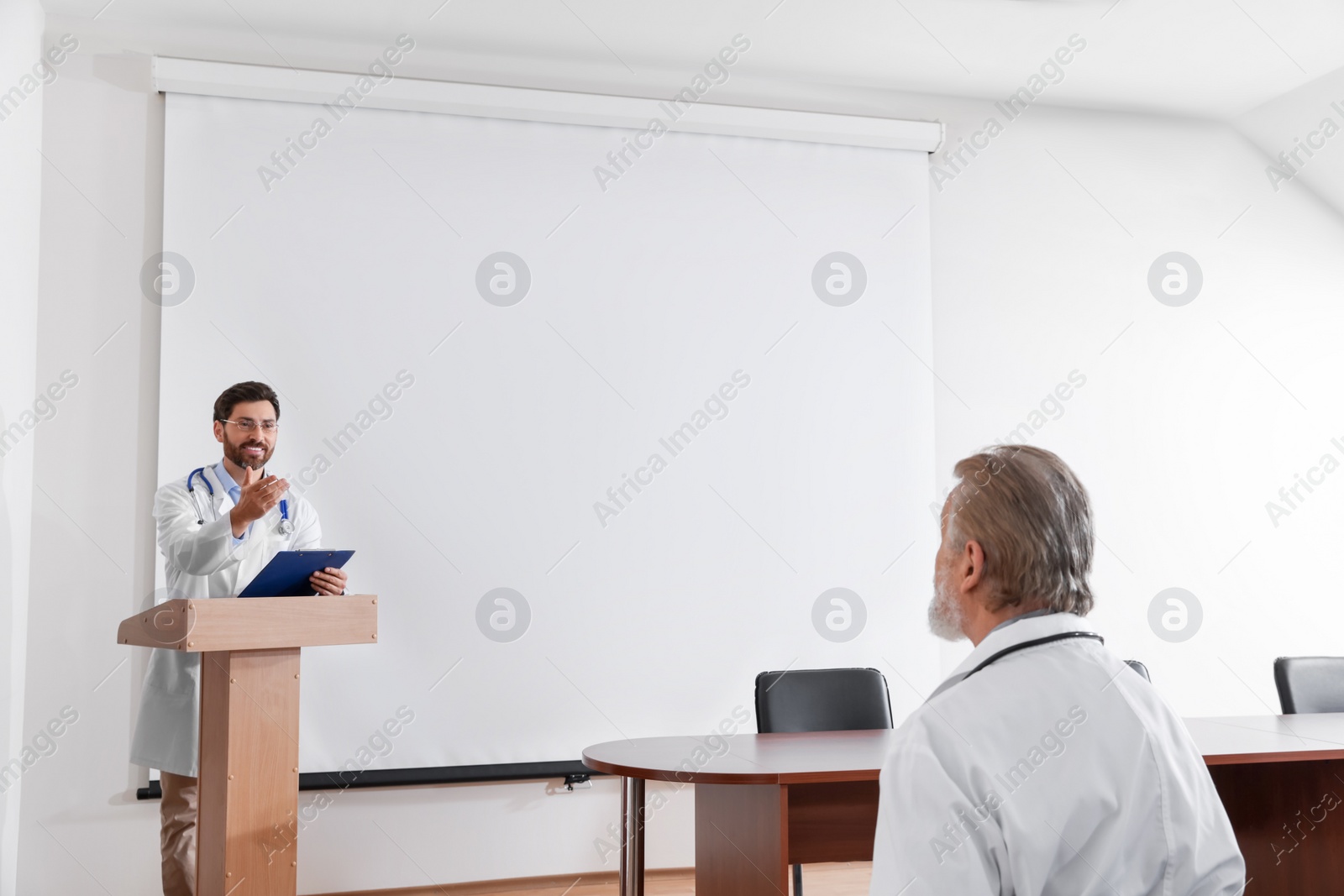 Photo of Doctor giving lecture in conference room with projection screen