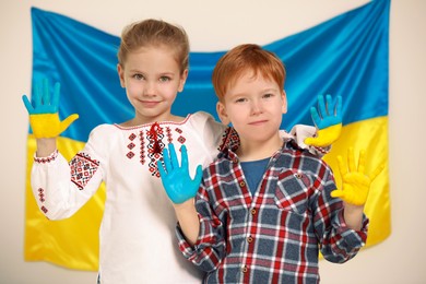 Little girl and boy with painted hands near Ukrainian flag. Love Ukraine concept