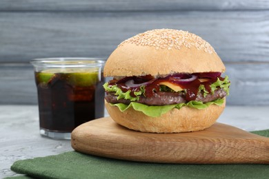 Photo of Delicious cheeseburger and drink on grey table, closeup